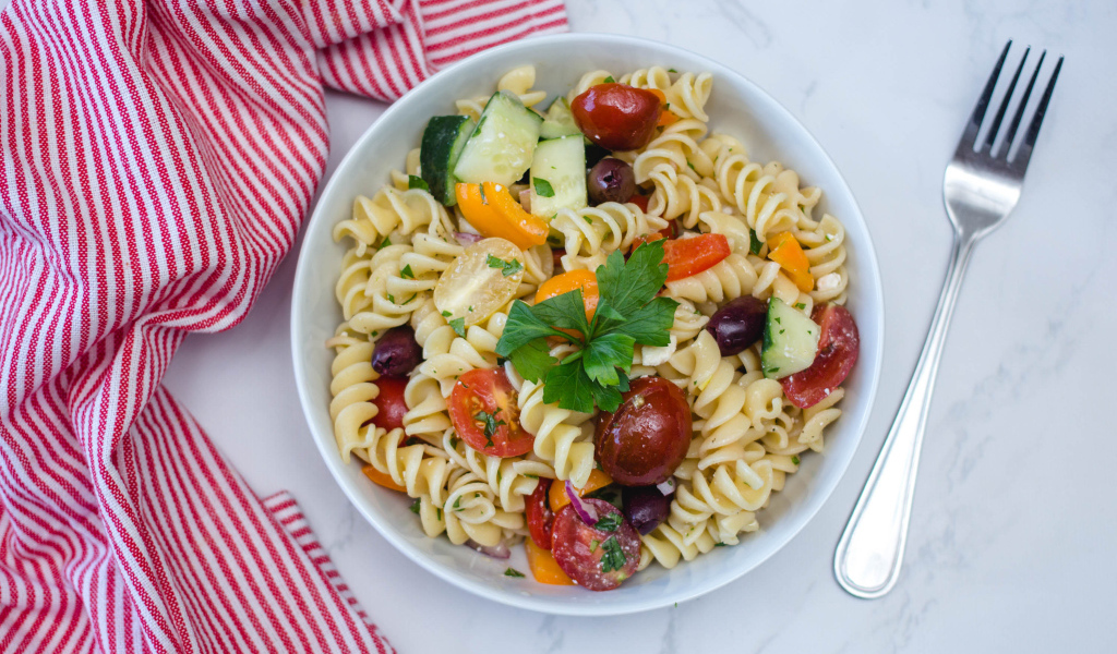 Макароны в тарелке с овощами на столе 