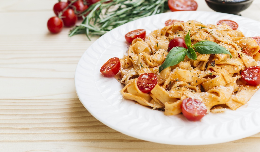 Паста с помидорами черри на белой тарелке