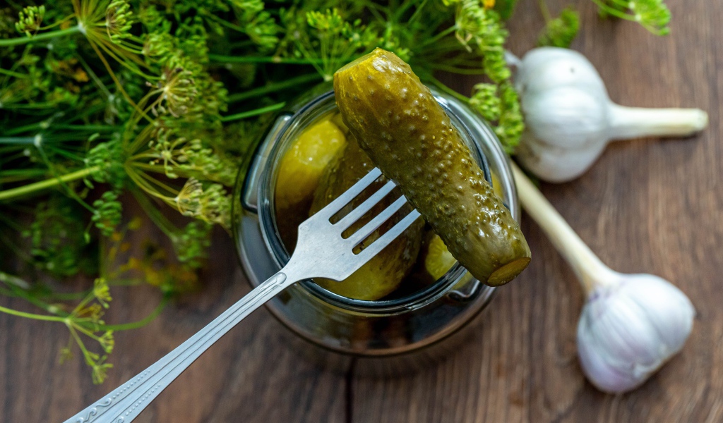 Маринованные огурцы в банке на столе с чесноком и укропом