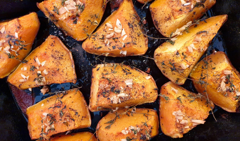 Куски жареной тыквы со специями на сковороде 