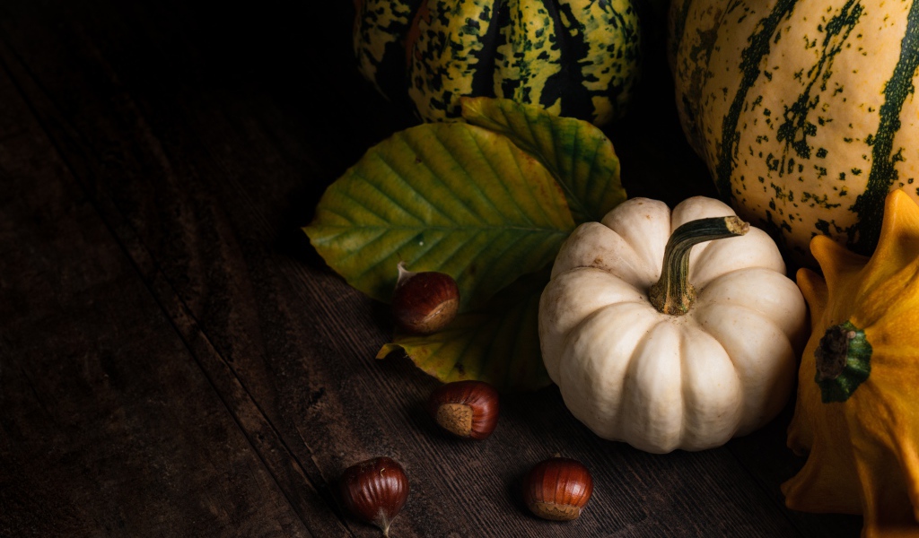 Тыква с каштанами на деревянном столе 