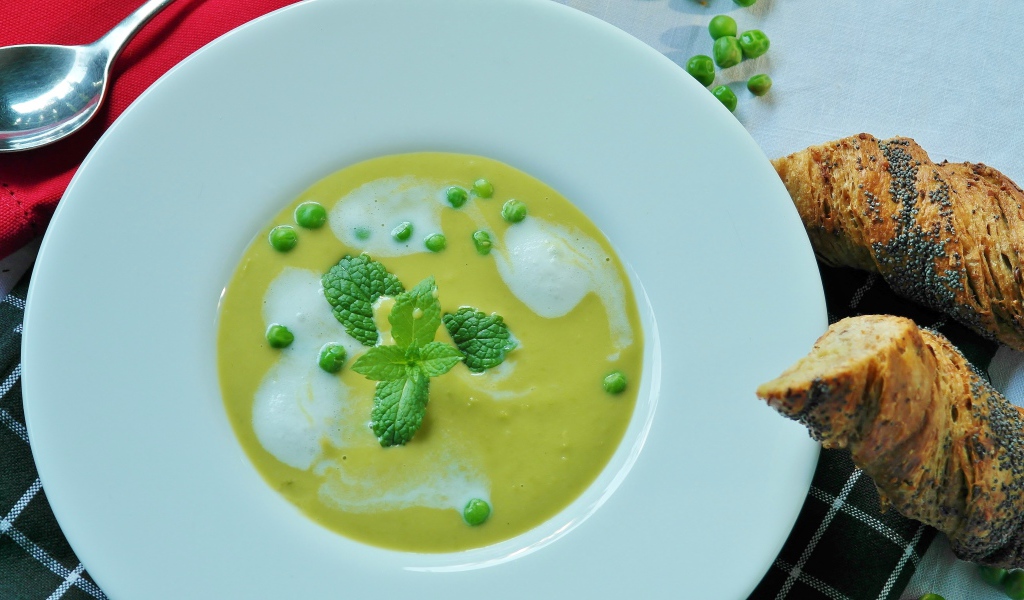 Суп пюре с зеленым горошком в белой тарелке 