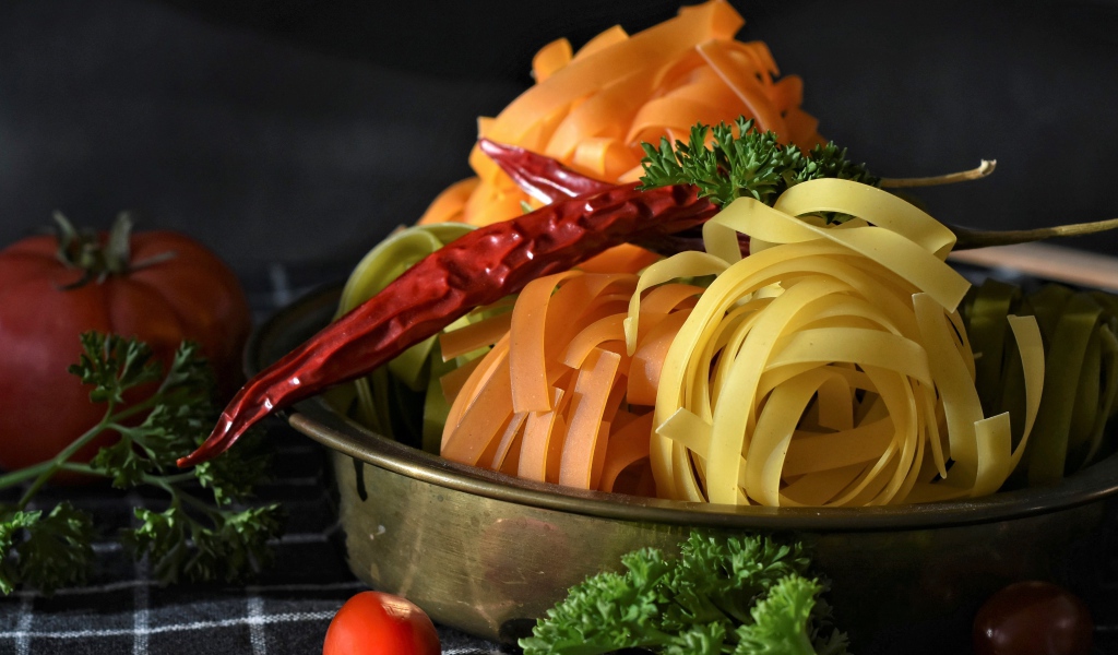 Сырая лапша на столе с острым перцем и петрушкой