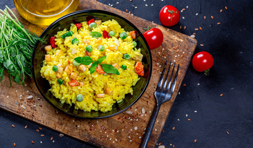 Рис с овощами на столе с маслом, зеленью и помидорами 