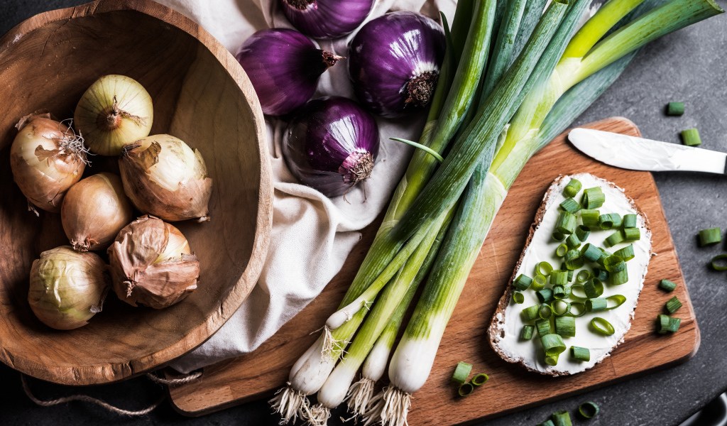 Бутерброд на столе с зеленым и репчатым луком