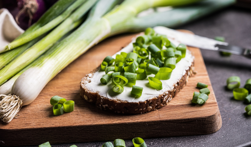 Бутерброд с маслом и зеленым луком на столе 