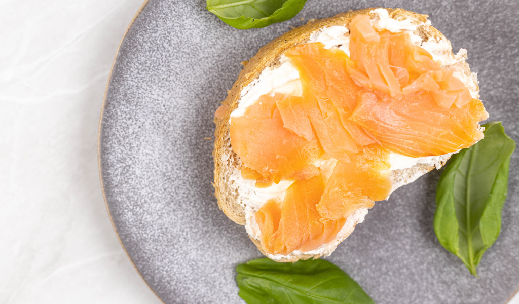 Бутерброд с сыром, красной рыбой и листьями базилика