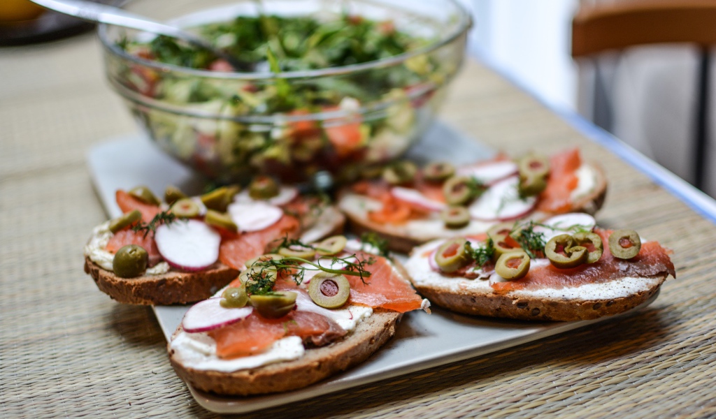 Бутерброды с маслом и красной рыбой на столе с салатом