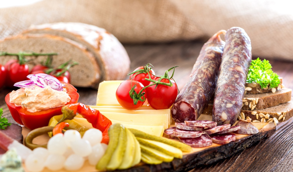 Колбаса на столе с огурцами, помидорами и перцем