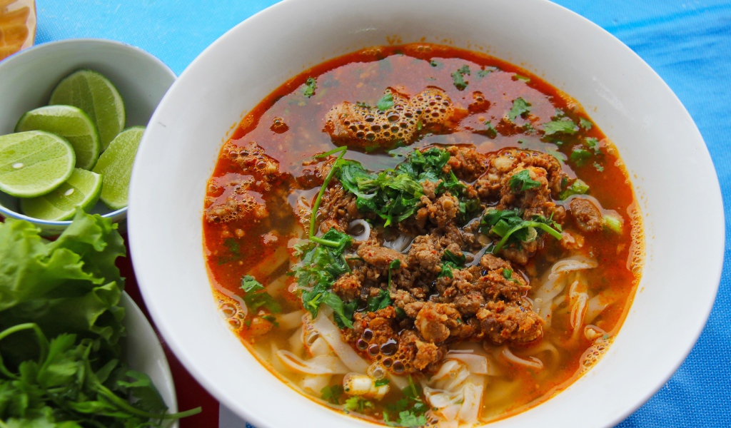 Spicy soup with noodles and meat in a plate with herbs