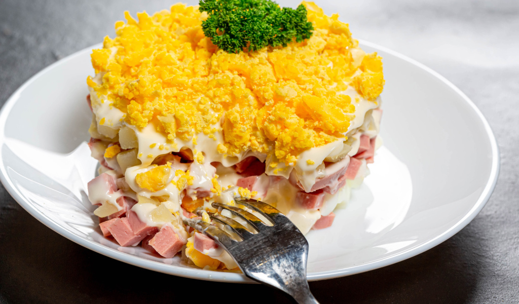 Вкусный салат на белой тарелке с вилкой