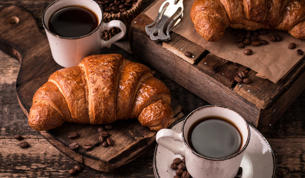 Две чашки кофе на столе с рогаликами и зернами 
