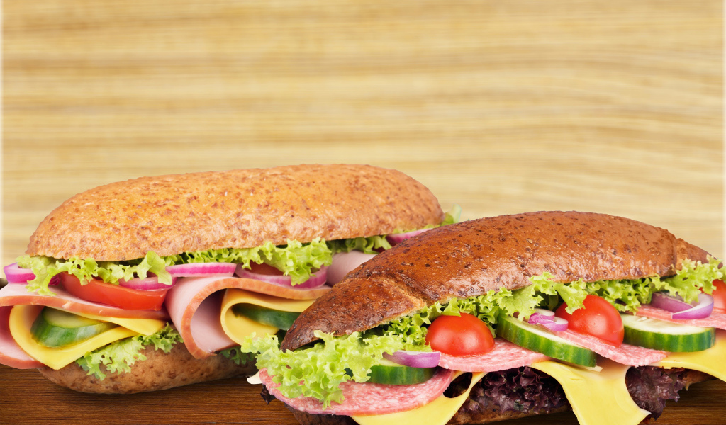 Два аппетитных сэндвича с колбасой и овощами на столе