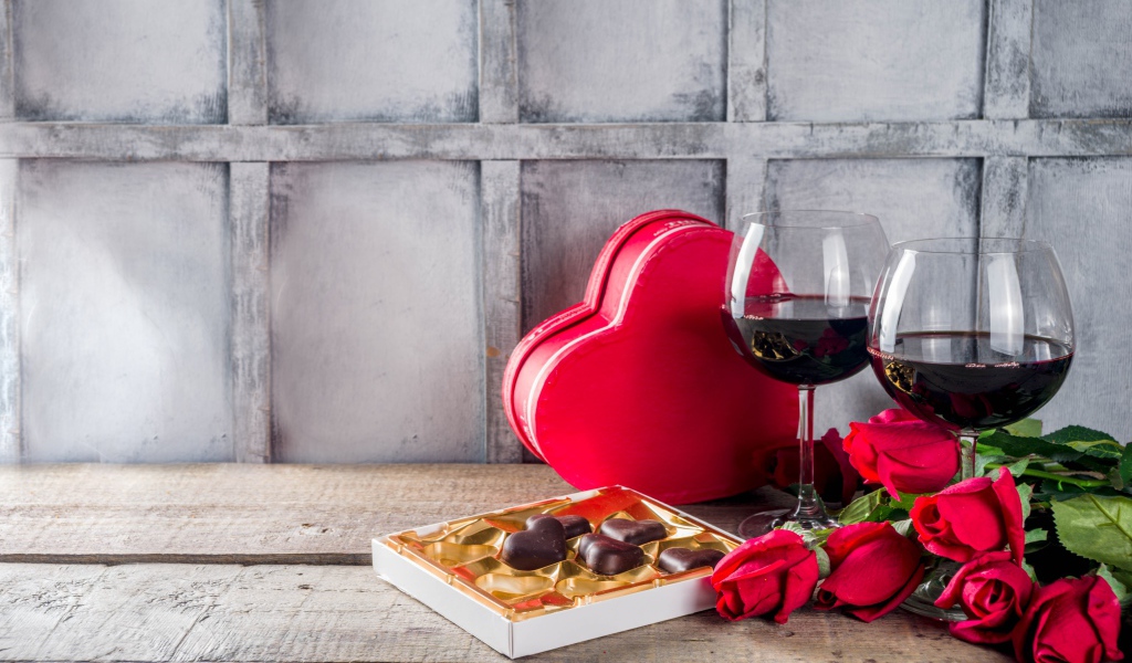 Два бокала вина, шоколадные конфеты и розы на столе для любимой 