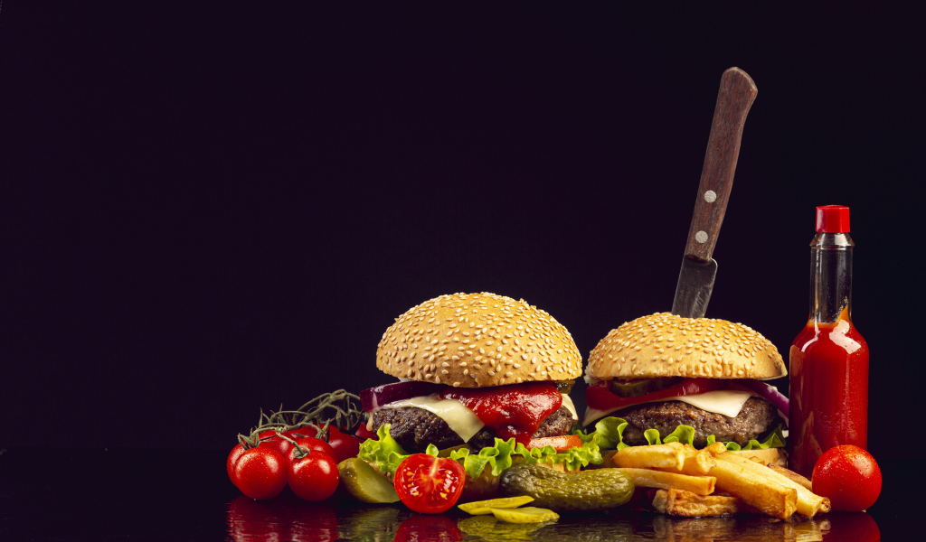 Два гамбургера на столе с ножом, овощами и кетчупом 
