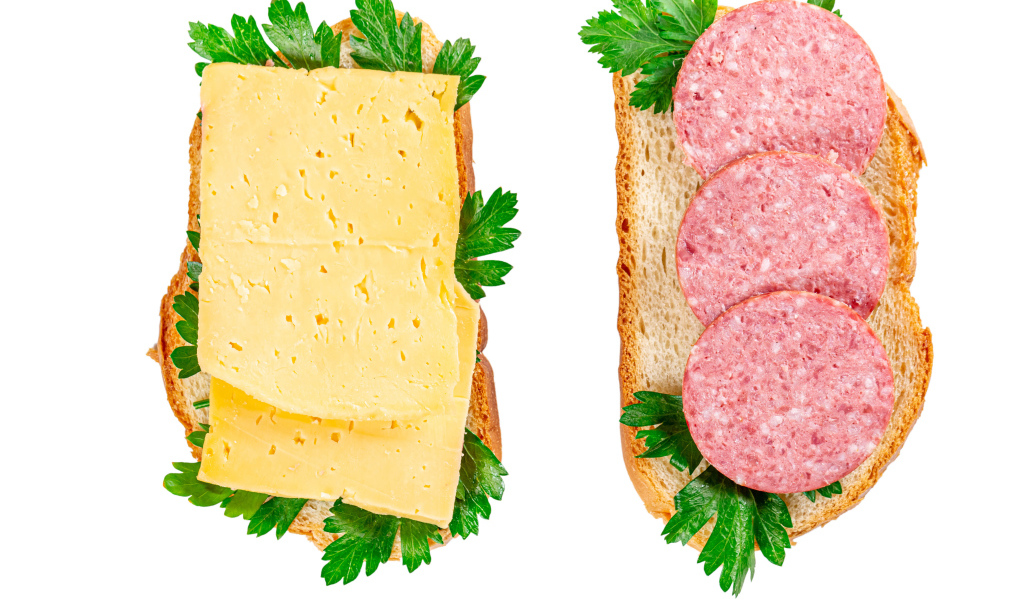 Два бутерброда с сыром,колбасой,петрушкой на белом фоне