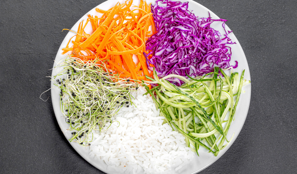 Овощи с рисом на большой  белой тарелке на сером столе 