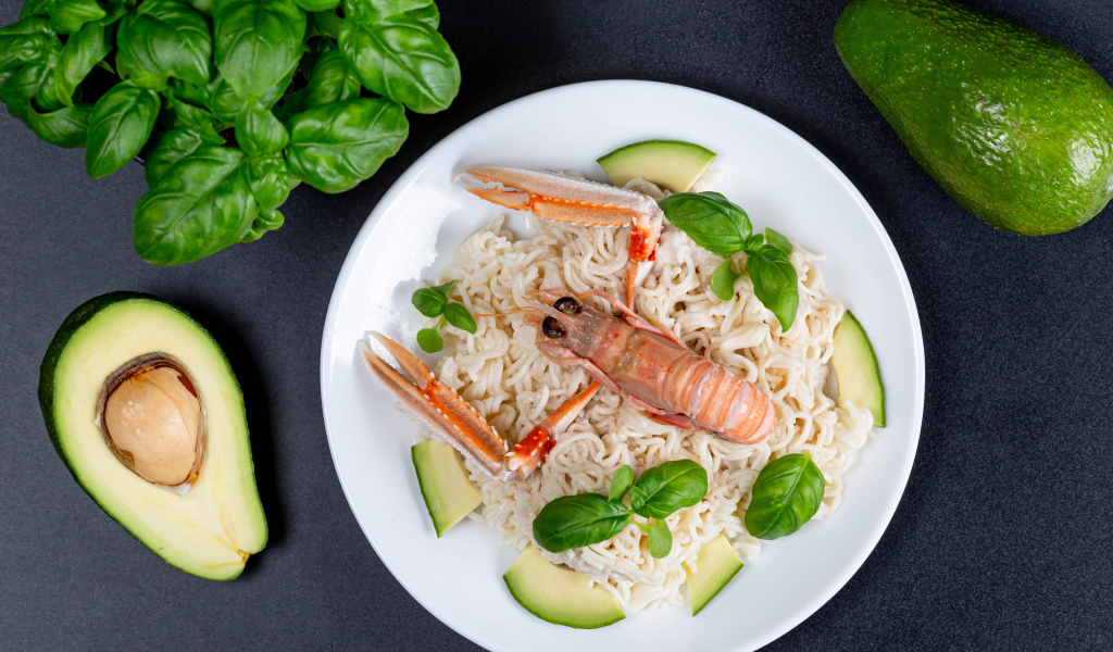 Vermicelli with lobster on a plate with avocado and basil leaves
