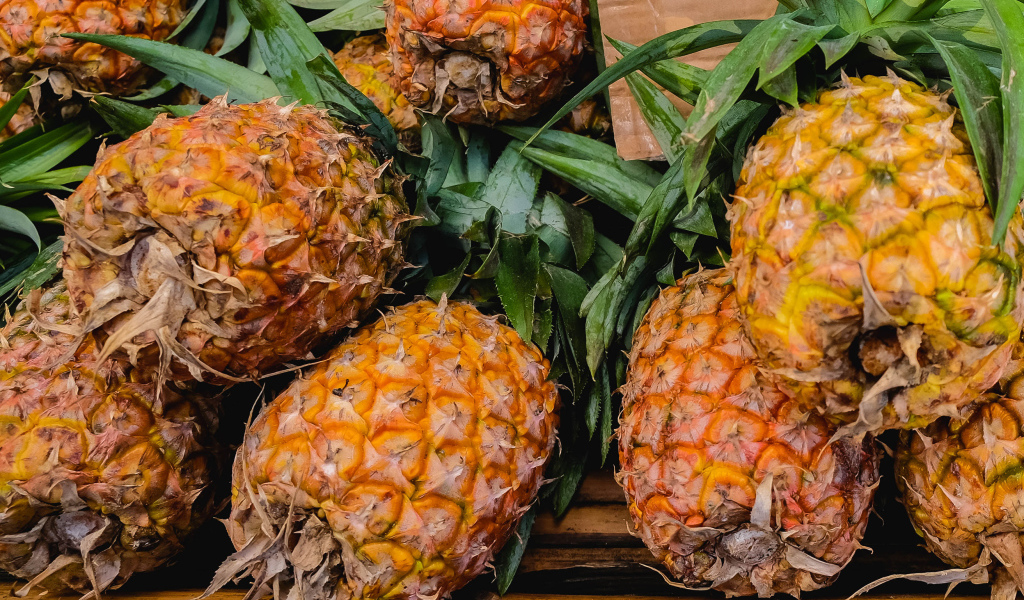 Много больших спелых ананасов на столе 