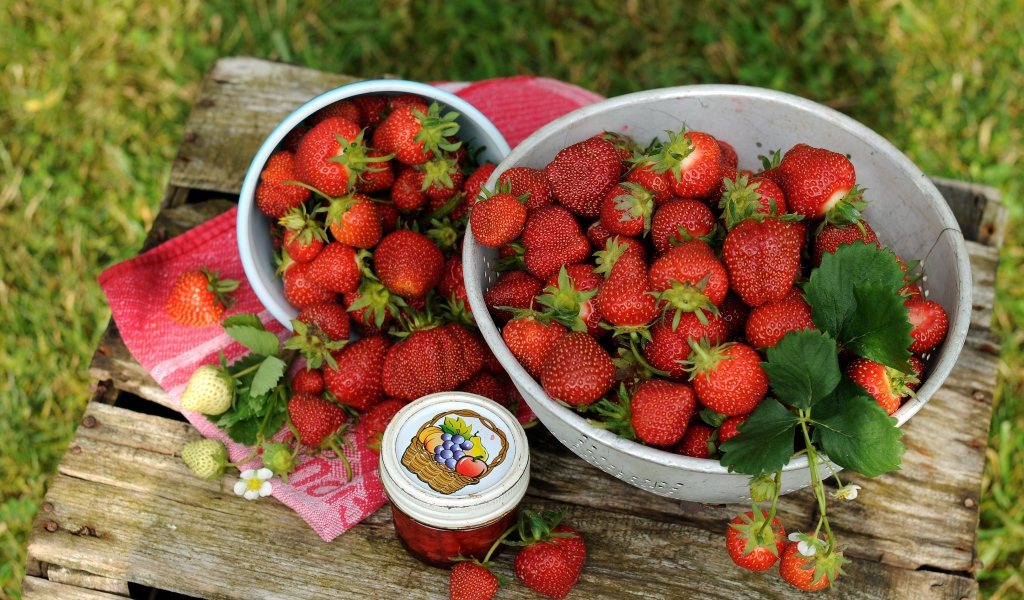 Много спелой ароматной клубники на столе с джемом 