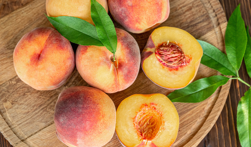 Аппетитные свежие персики на деревянной доске