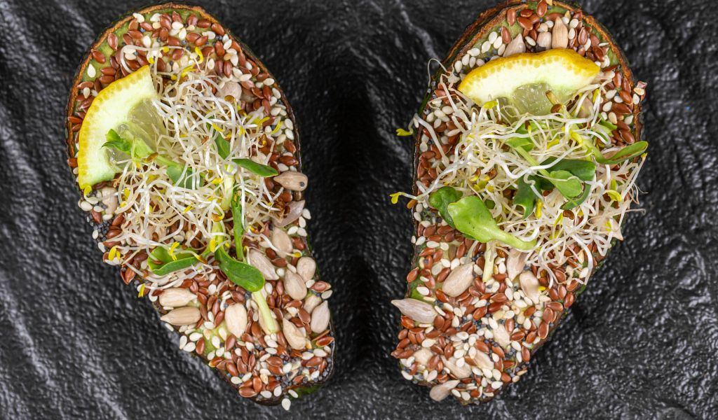 Половинки авокадо с проросшими зернами на столе