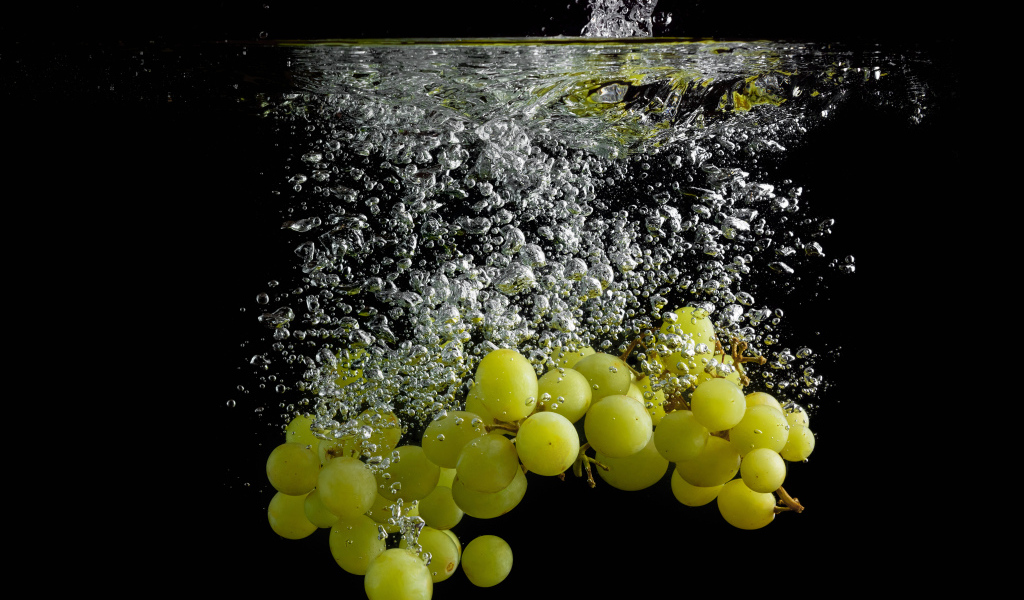 Ягоды белого винограда в воде на черном фоне