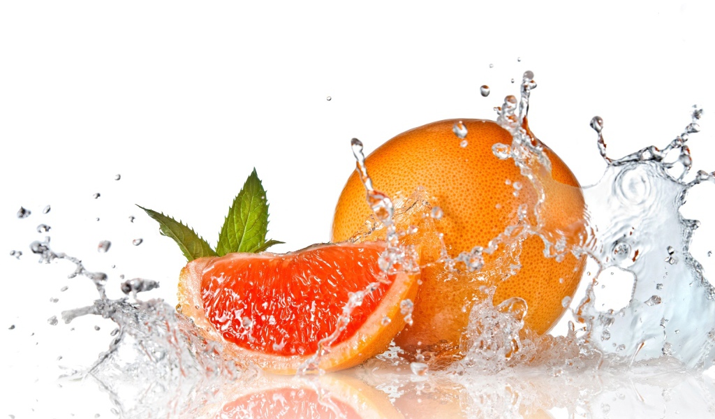Большой спелый апельсин в брызгах воды на белом фоне