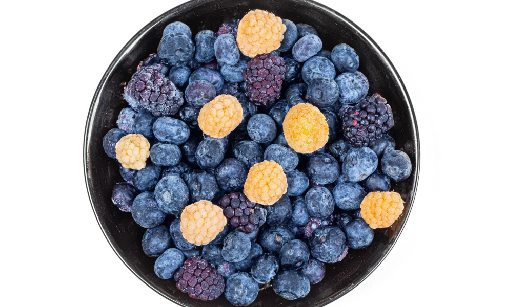 Миска с замороженными ягодами черники и ежевики на белом фоне