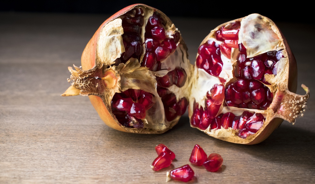 Разломанный красный гранат на столе 