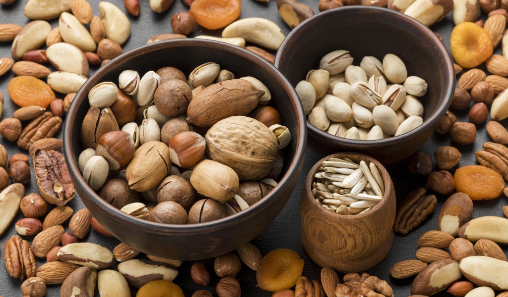 Разные виды орехов на столе в мисках 