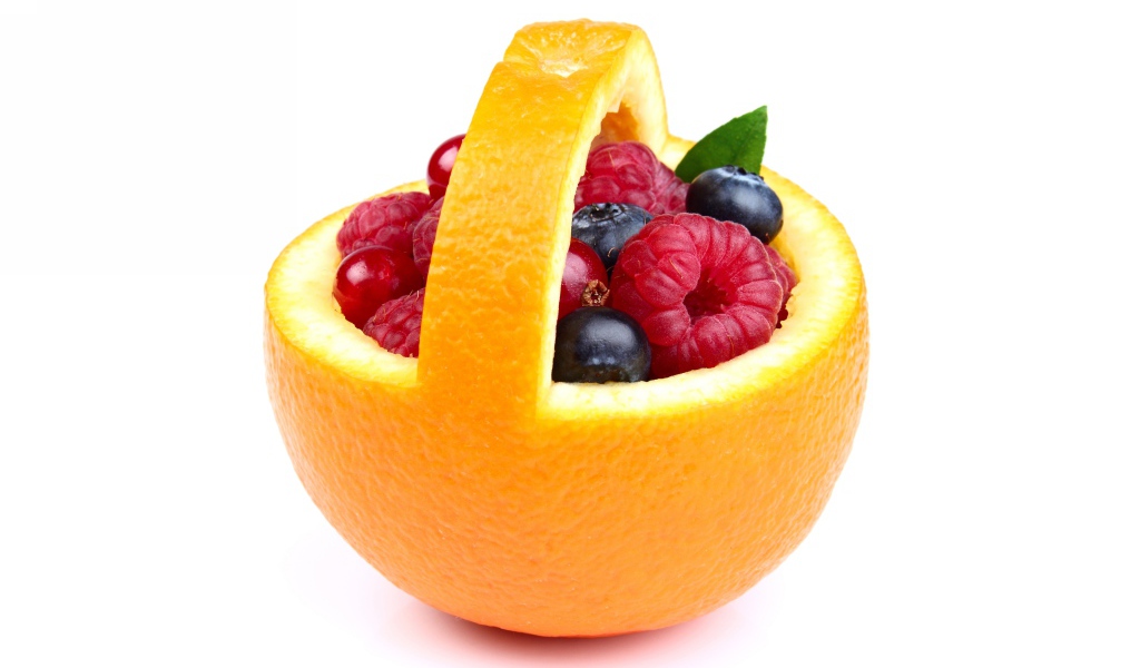 Свежие ягоды в кожуре апельсина на белом фоне