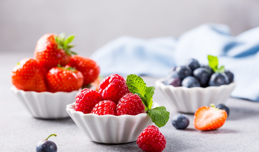 Свежие ягоды малины, клубники и черники на столе