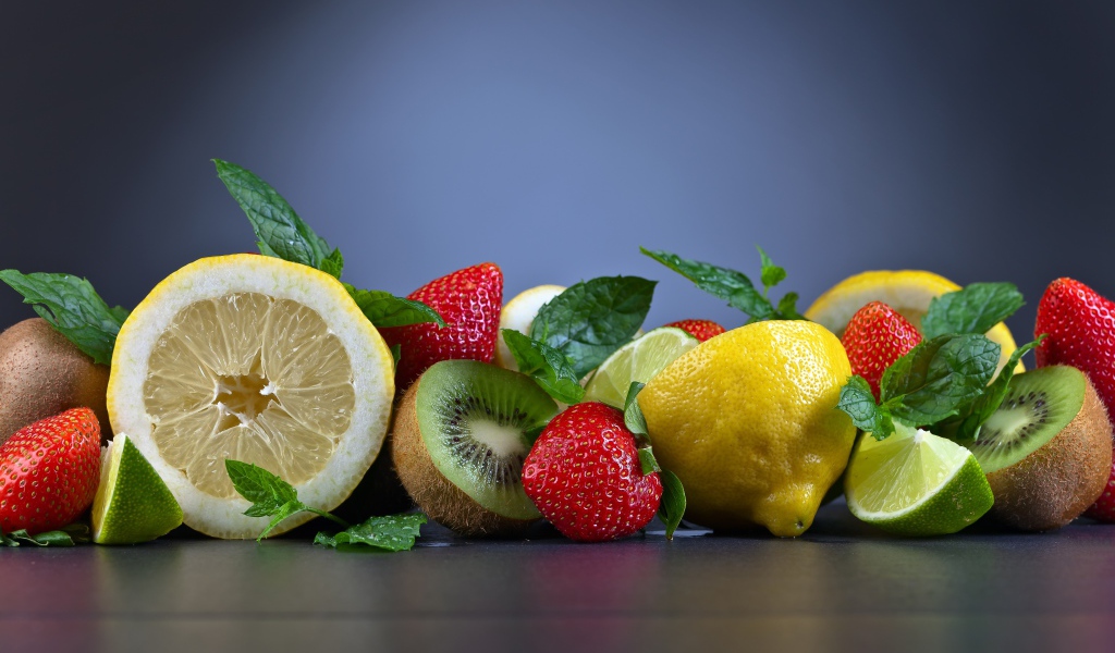 Лимоны на столе с киви и ягодами клубники 