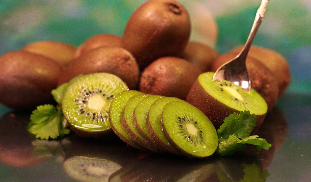 Много спелых плодов киви на столе с ложкой 