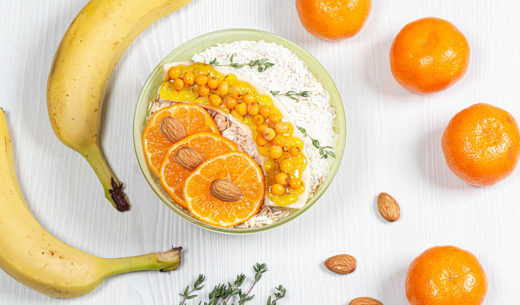 Мюсли с облепихой, бананом и апельсином на столе с фруктами