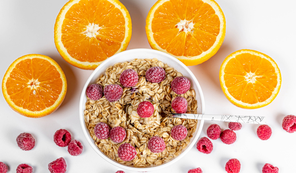 Овсяные хлопья с малиной на белом фоне с апельсинами