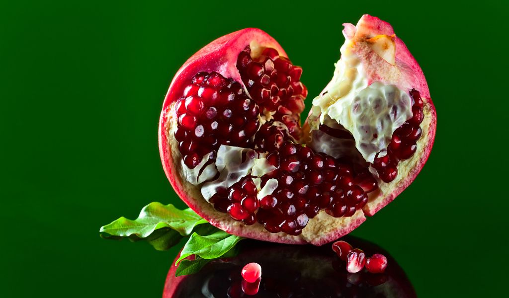 Очищенный гранат на зеленом фоне