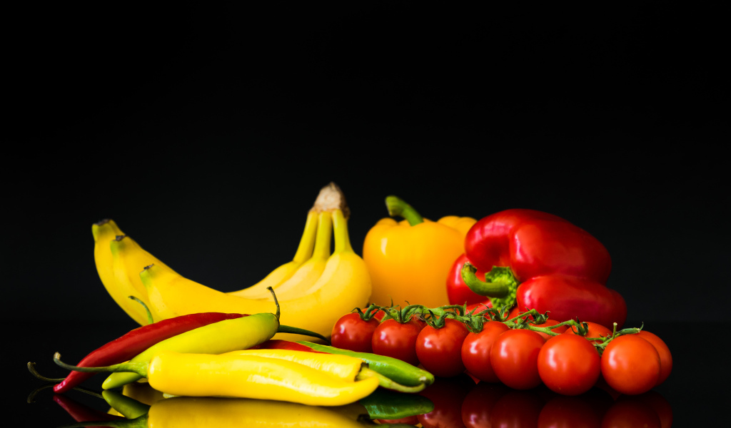 Перец, помидоры и бананы на черном фоне