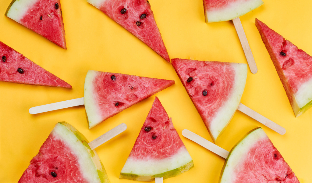 Кусочки арбуза на палочках на желтом фоне