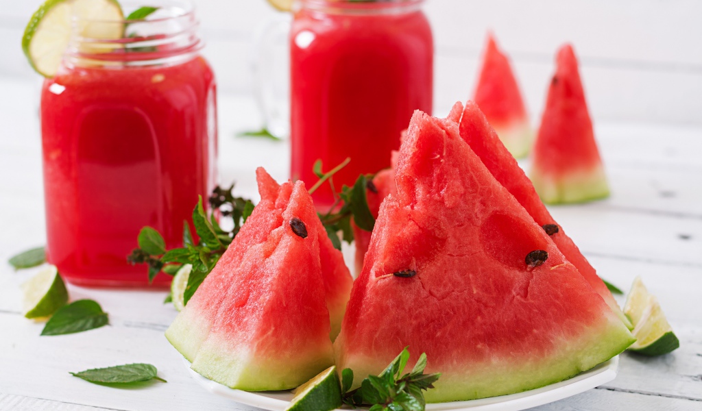 Куски арбуза с мятой на столе с соком 