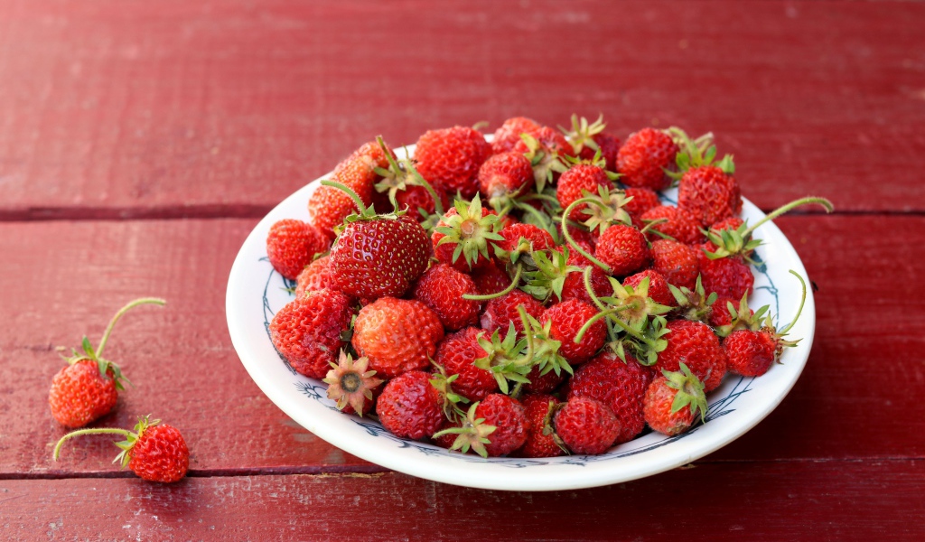 Тарелка со спелой домашней клубникой на столе
