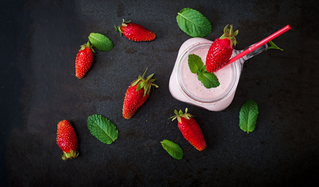 Красная клубника на черном столе с йогуртом