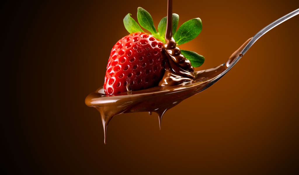 Красная клубника на ложке с молочным шоколадом