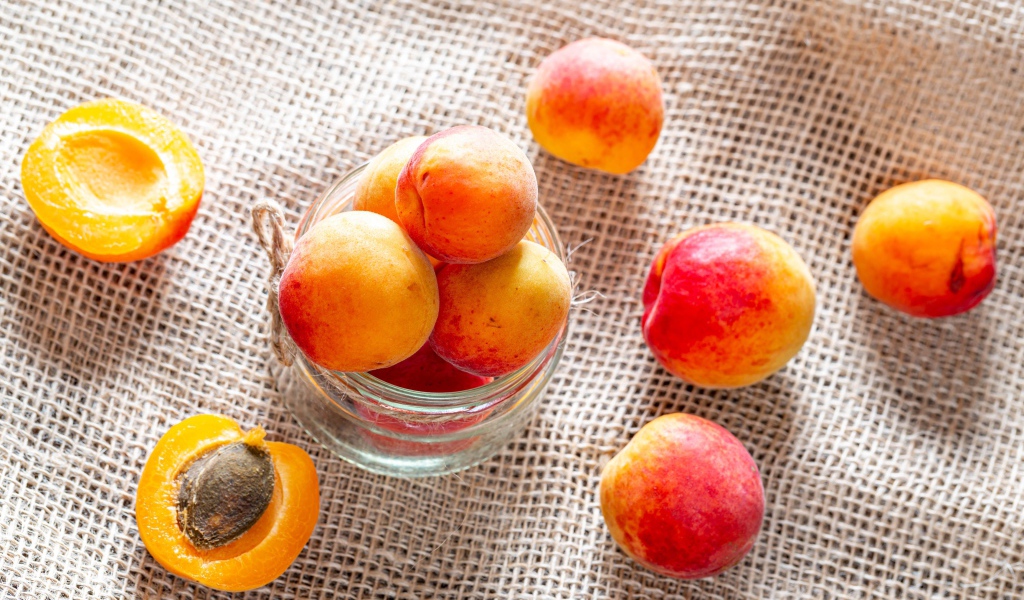 Спелые абрикосы в стеклянной банке на столе 