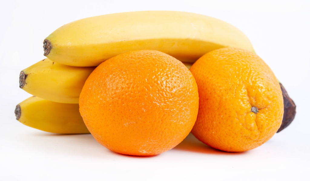 Спелые апельсины и бананы на белом фоне 