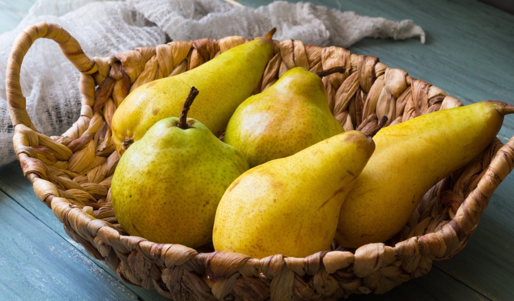 Спелые груши лежат в корзине на столе