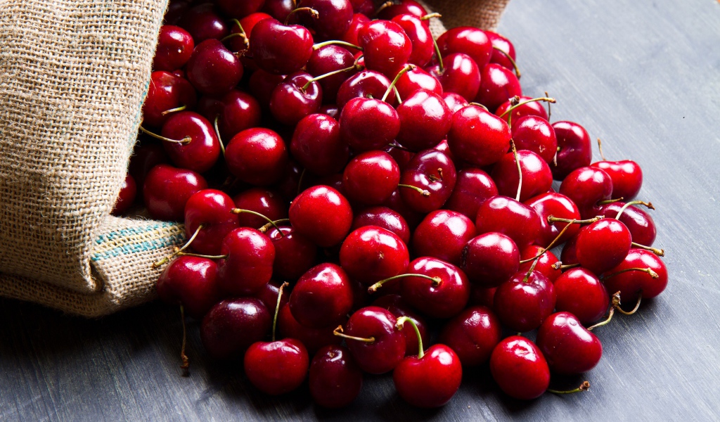 Спелые красные черешни в мешке на столе 