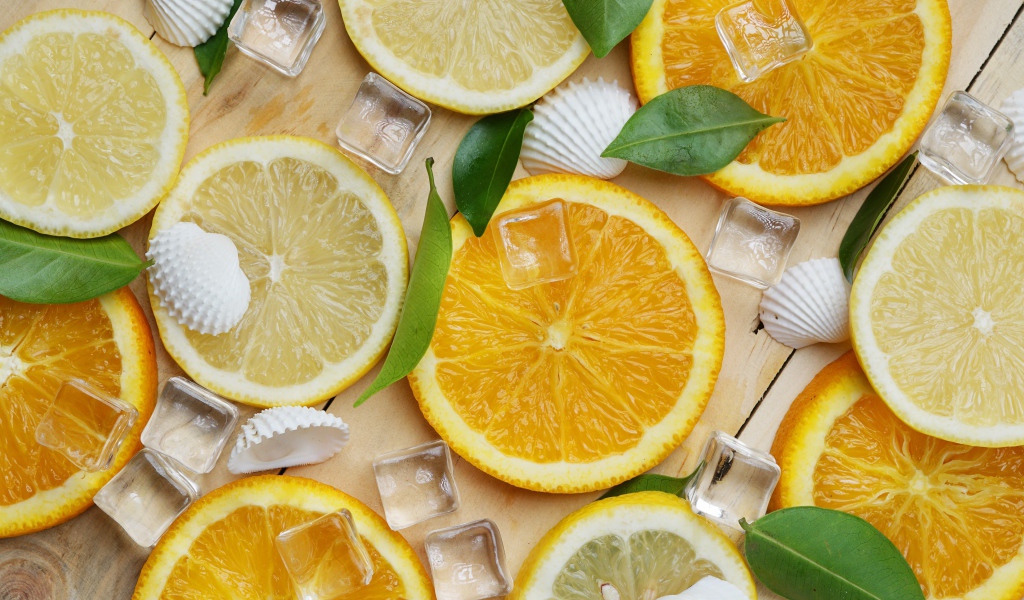 Кусочки апельсина и лимона на столе с кубиками льда и ракушками