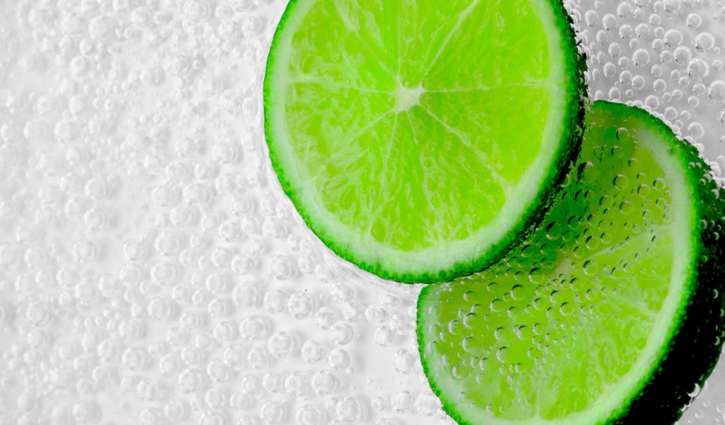 Два куска лайма в пузырях в воде 